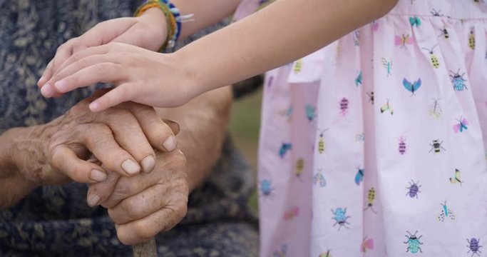 HELPING HAND. Detail of a Child's Hands Holding the Senior Woman Hands