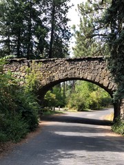 Fototapeta premium Old Stone bridge in a park surrounded by green trees