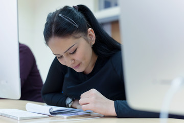Beautiful female  IT student working at her computer lab.  Female student listening lesson from their professor. Education and technology concept.