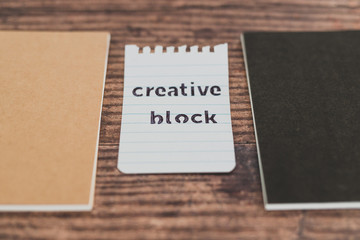 creative block or writer's block, notepads on wooden desk with text doodle on piece of paper