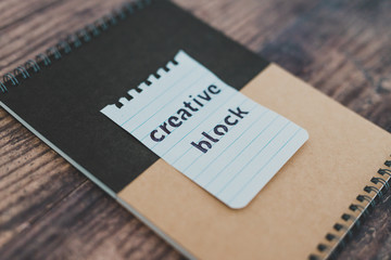 creative block or writer's block, notepads on wooden desk with text doodle on piece of paper