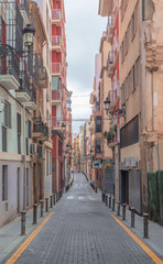 a long narrow traffic-free street creeps between the buildings early in the morning