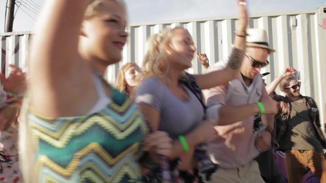 Crowd of energetic young friends dancing and cheering at summer music festival