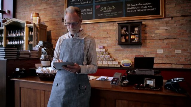 Male senior business owner using digital tablet in shop