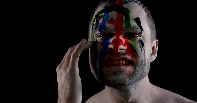 actor smears colorful paint over face expressing emotions