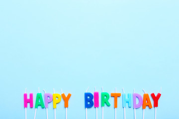 Happy birthday candles on blue background with copy space