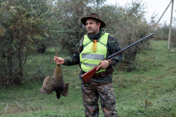 Silhouette of a hunter with a gun in the reeds against the sun, an ambush for ducks with dogs	