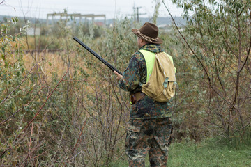 Silhouette of a hunter with a gun in the reeds against the sun, an ambush for ducks with dogs	