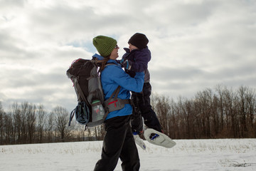Fototapeta na wymiar Mom and Young Boy Swinging With Snowshoes