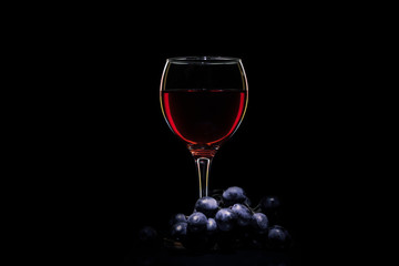 Glass with wine and grapes on a black background.