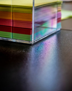 Posting notes rack gives reflections from the sun that looks like a tiny rainbow, colorful papers, reclections, acrylic box, sticky notes, work desk in office