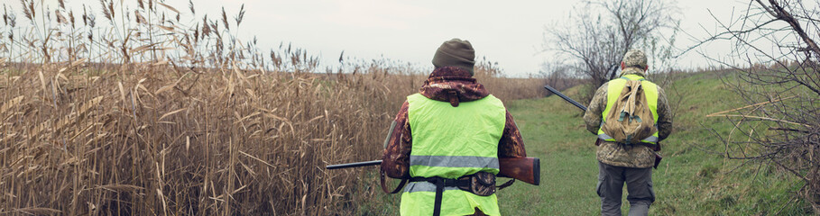 Hunting period, autumn season open. A hunters with a gun in his hands in hunting clothes in the...