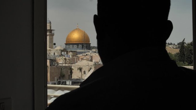 Silhouette of man looking from window at Western Wall Plaza and Dome of Rock