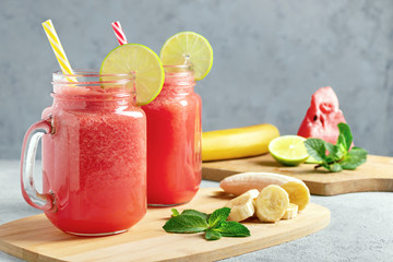 Watermelon smoothie with banana, lime and mint in mug jars on a cutting board. Healthy eating concept