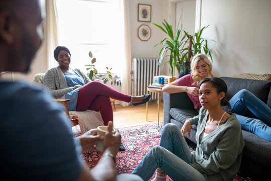 Young Adult Friends Relaxing, Hanging Out In Apartment Living Room