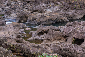 Fototapeta na wymiar Hilo, Hawaii, USA. - January 9, 2012: Brown rock river bed above Rainbow falls show only a bit of water.