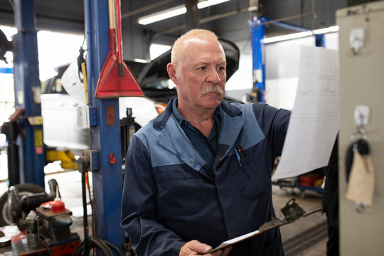 Mechanic reading document in automobile workshop
