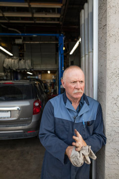 Portrait of mechanic wiping hands on cloth outside garage