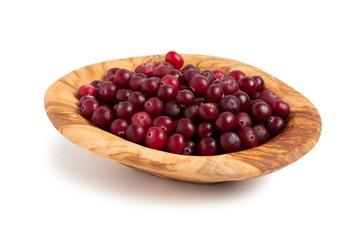 Ripe cranberries in a bowl of olive wood isolated on white background