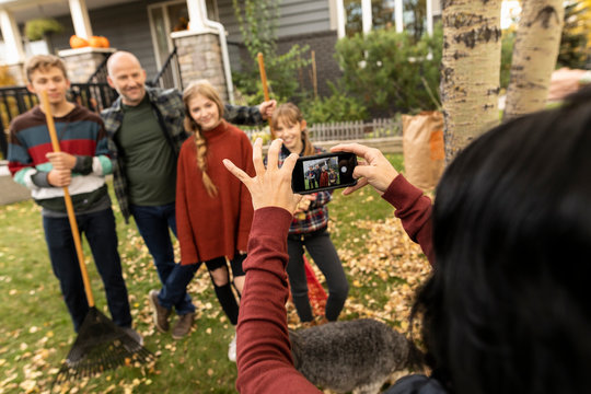 Mother Photographing Family Doing Yard Work