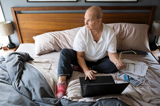 Cancer survivor shopping online with laptop on bed