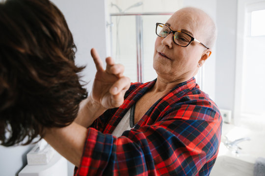 Female cancer survivor trying on wig in bathroom