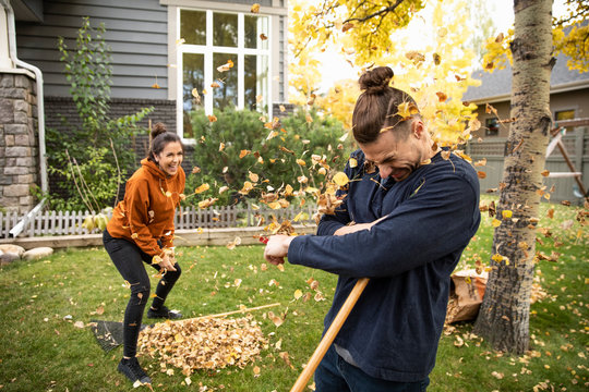 Young couple playing with autumn leaves in yard