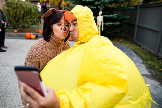 Man in chicken costume pouting for selfie with wife on Halloween