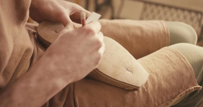 Traditional bespoke shoemaker measuring marking leather insole on wooden shoe last with ruler pencil