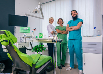 Fototapeta premium Team of three happy dentists proudly posing in a dental office