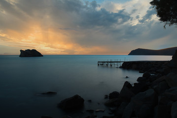 Fototapeta premium dilapidated, rundown pier with island in the background at sunset