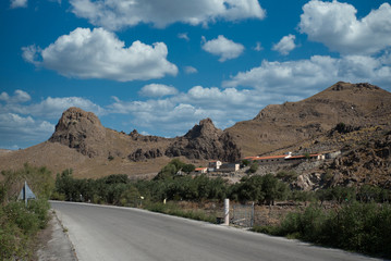 Farm buildings on a mountain with blue sky and clouds in the background