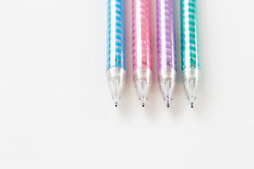 closeup blue, pink, purple and green mechanical pencils on white background