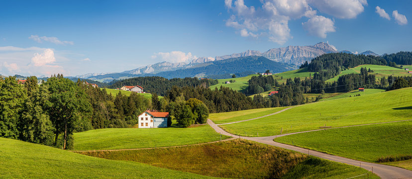 Beautiful view of idyllic mountain scenery in the Alps with green meadows and famous Saentis summit in the background on a sunny day with blue sky and clouds in summer, Appenzellerland, Switzerland