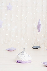 A magical beautiful holiday cake made of gray stars, white cream and lilac biscuit. Birthday gift. Birthday party. Shiny wall background made of small led lamps.