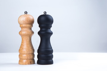 salt and pepper wooden shakers, grinders on a white table with white background 