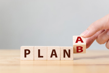 Hand flip over wooden cube block word plan A to plan B