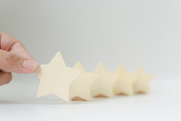 Hand putting wooden five star shape on white background. The best excellent business services...