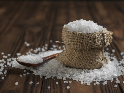 A Bag Of Coarse Salt And A Wooden Spoon On A Rustic Table.