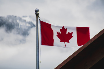 A picture of Canada flag waving against the snow-covered mountain.   Squamish BC Canada