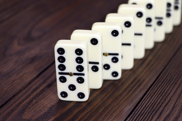 Dominoes game on a wooden table, brown background. Board game domino. Gambling.