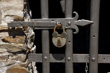 padlock on old medieval gate with metal bars