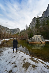 Young woman enjoying view of granite rock formations reflected in Mirror Lake in Yosemite National Park, California.