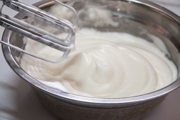 Fototapeta na wymiar Beating egg white with electric whisk, elevated view. Egg white used for preparing cake.