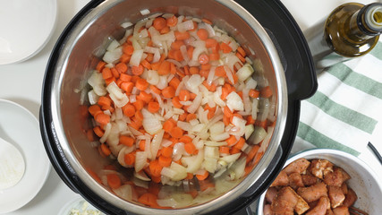 Saute chopped carrot and onion in a multicooker. Cooking rice with meat and vegetables  in pressure multi cooker step by step, top view.