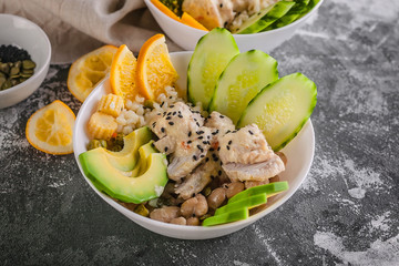 Close up Buddha bowl with chicken meat, bulgur, white beans, quinoa, avocado, lemon and fresh cucumber.
