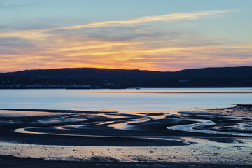 Zigzag shape tidal marks on sunset and mountain on the background.