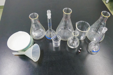 Assorted chemistry lab equipment. Erlenmeyer, balls, funnels and beaker. Black background