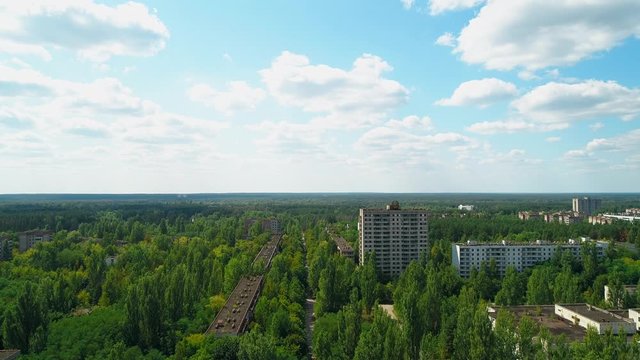 Aerial view of abandoned buildings and streets in city Pripyat near Chernobyl nuclear power plant. Cyrillic inscription "Let the atom be a worker, not soldier". Sign of USSR on roof. 4K drone footage.