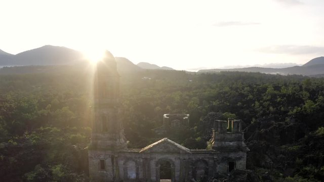 Aerial shot revealing the sun behind church ruinas, Paricutin